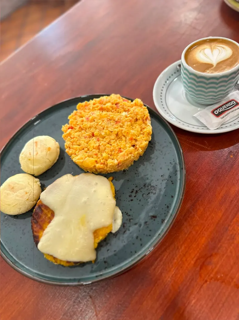Desayuno con arepas, huevos revueltos y un café con arte latte
