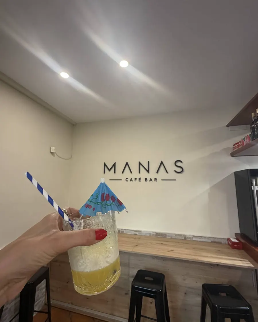 Cóctel con sombrilla azul junto a la barra de Manas