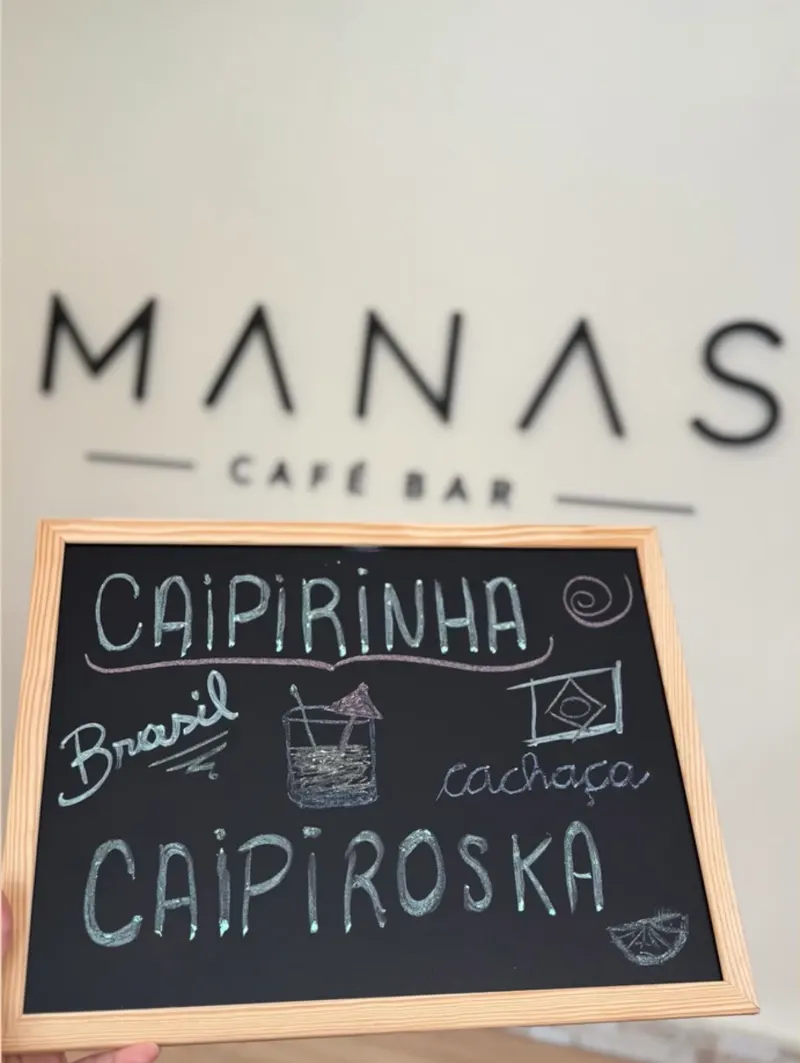 Pizarra con caipirinha y caipiroska frente al logo de Manas
